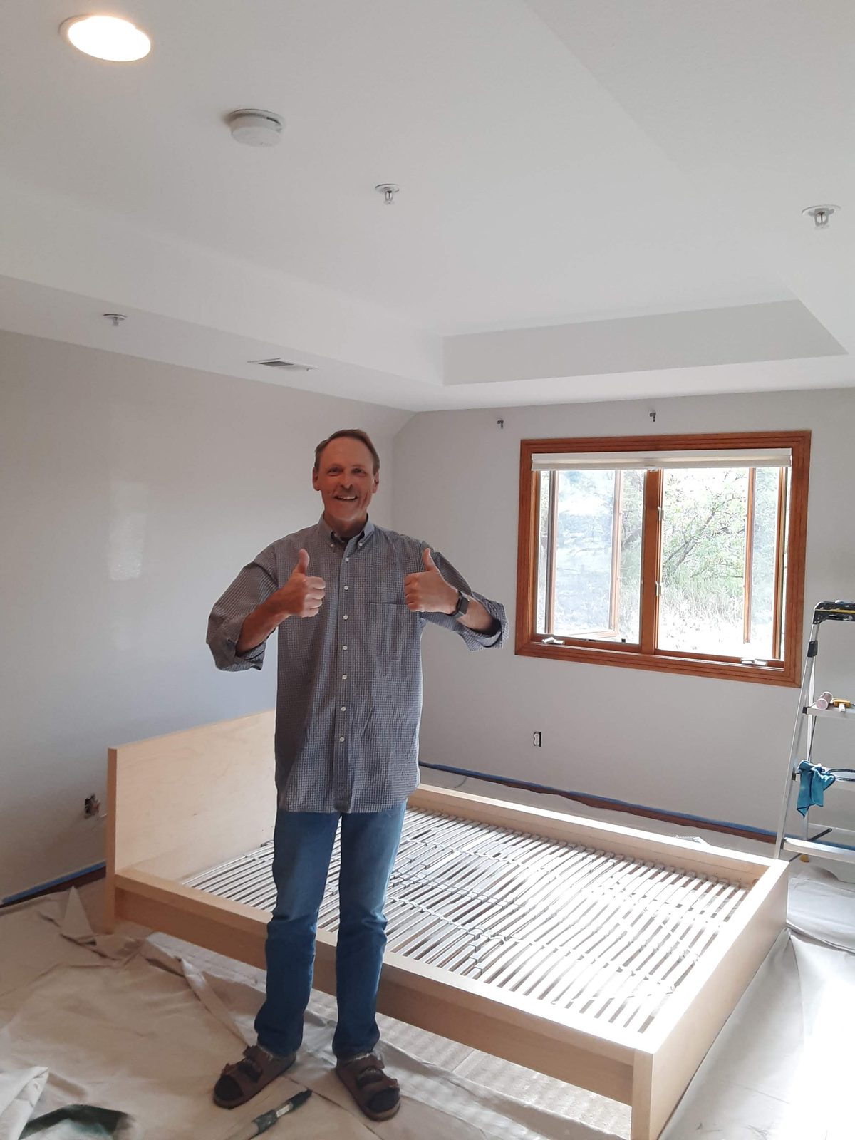 Homeowner giving two thumbs-up in his freshly painted bedroom